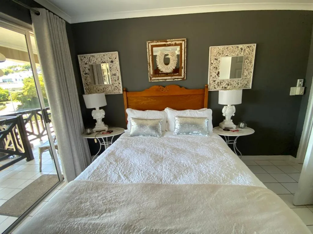 Master bedroom with queen bed, dark walls, and balcony access