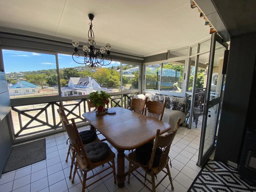 Enclosed deck with dining table, chairs, and scenic coastal town views