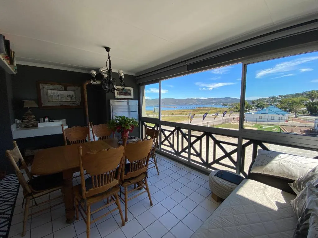Covered outdoor deck with dining table, lounge seating, and scenic lagoon views