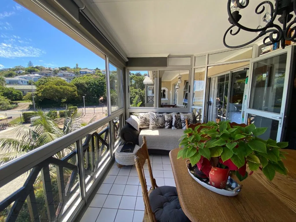 Covered patio with seating, potted plants, and scenic neighborhood views