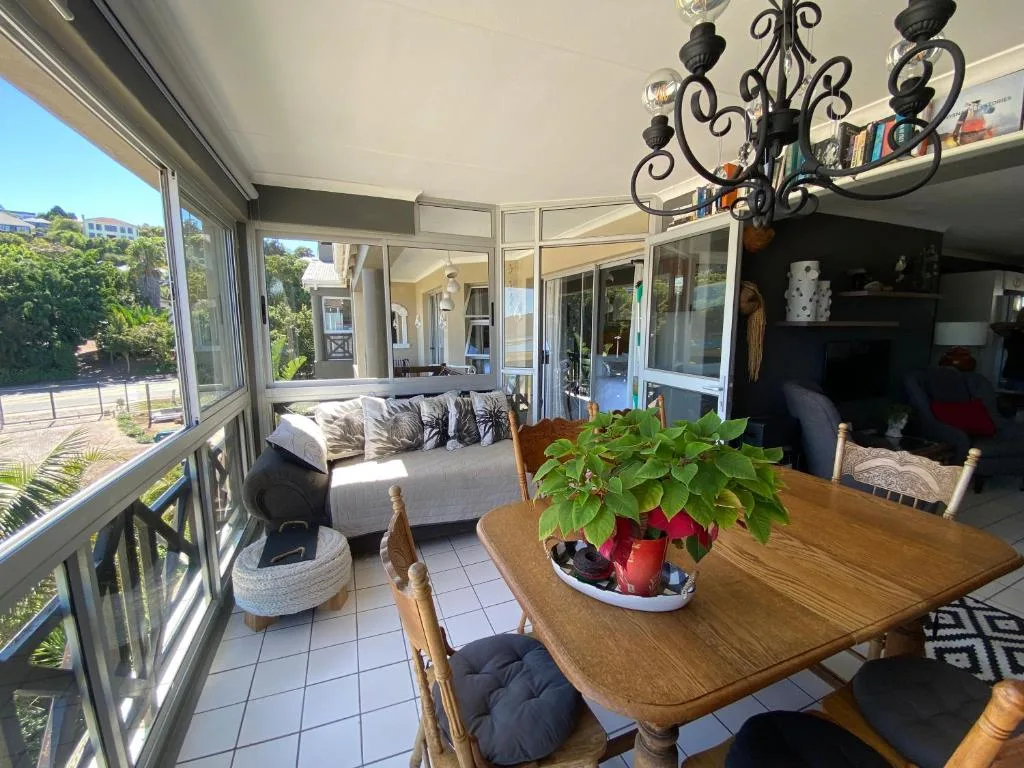 Enclosed deck with dining table, seating, and garden views through large windows