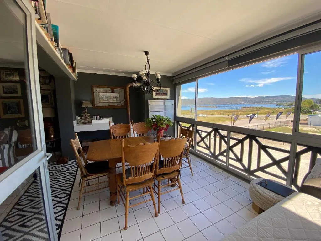 Dining area with wooden table, chairs, and panoramic lagoon views
