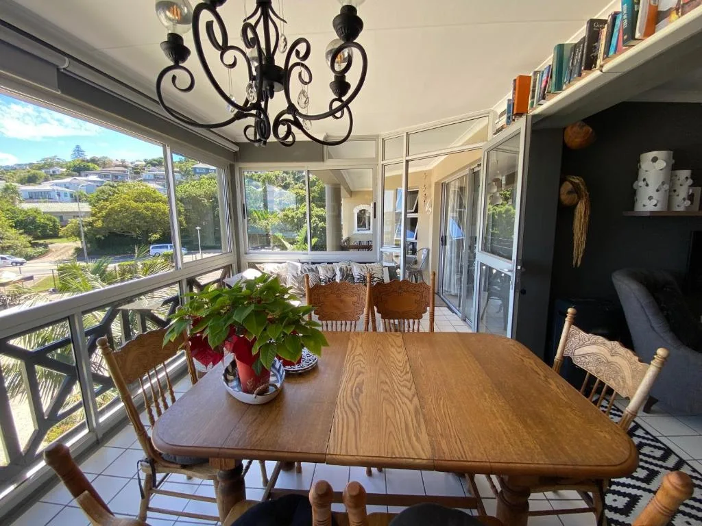 Wooden dining table with chairs overlooking Knysna lagoon through large windows