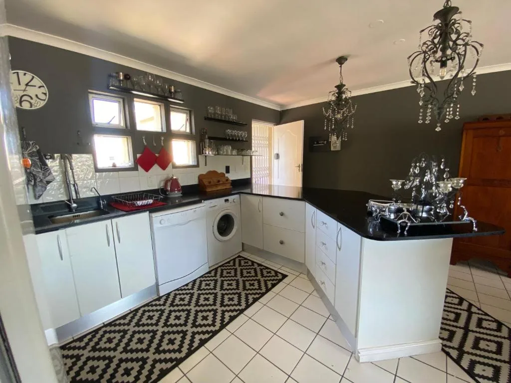 Modern kitchen with white cabinetry, black countertops, and decorative chandeliers