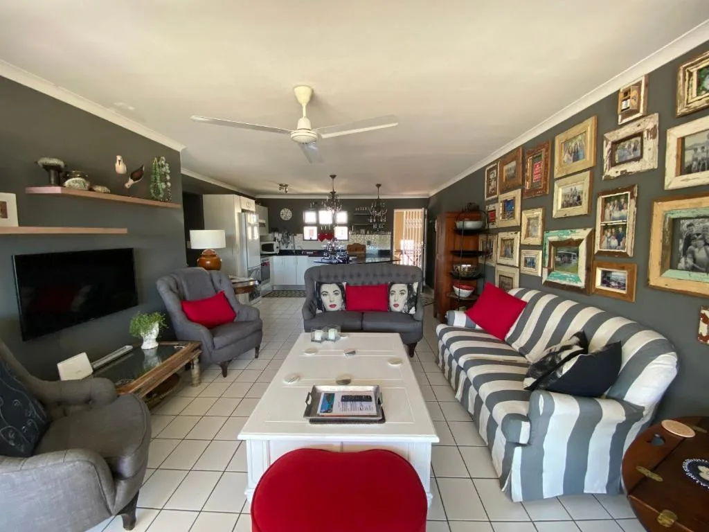 Spacious living room with gray walls, striped sofa, red accents, gallery wall