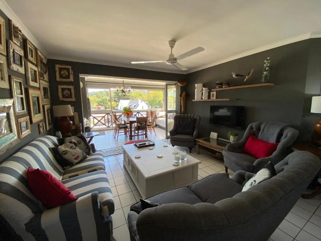 Spacious lounge with striped sofa, dark walls, and ocean view access through glass doors