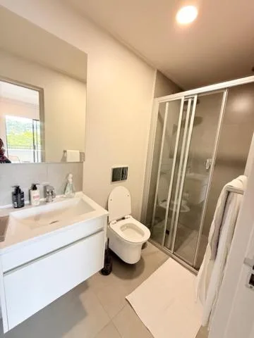 Modern bathroom with white vanity, toilet, and glass shower enclosure