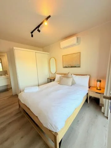 Bright bedroom with white bedding, wooden bed frame, and modern fixtures
