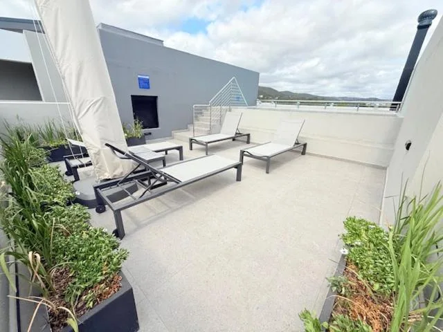 Rooftop terrace with loungers, seating, and landscaping overlooking mountains