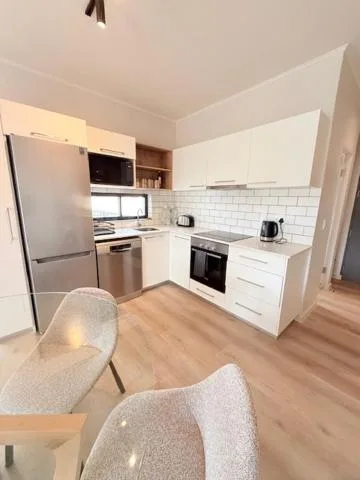 Modern white kitchen with stainless steel appliances and dining chairs