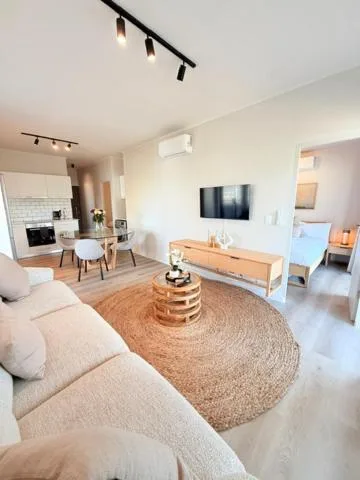 Spacious open-plan lounge with cream sofa, TV, and natural lighting