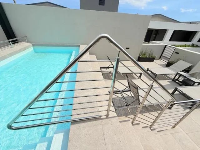 Outdoor swimming pool with lounge chairs and modern white architecture
