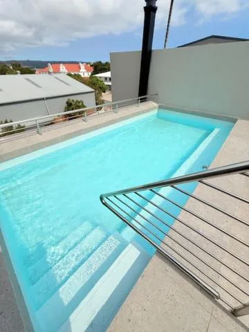 Bright turquoise swimming pool on modern rooftop deck with coastal views