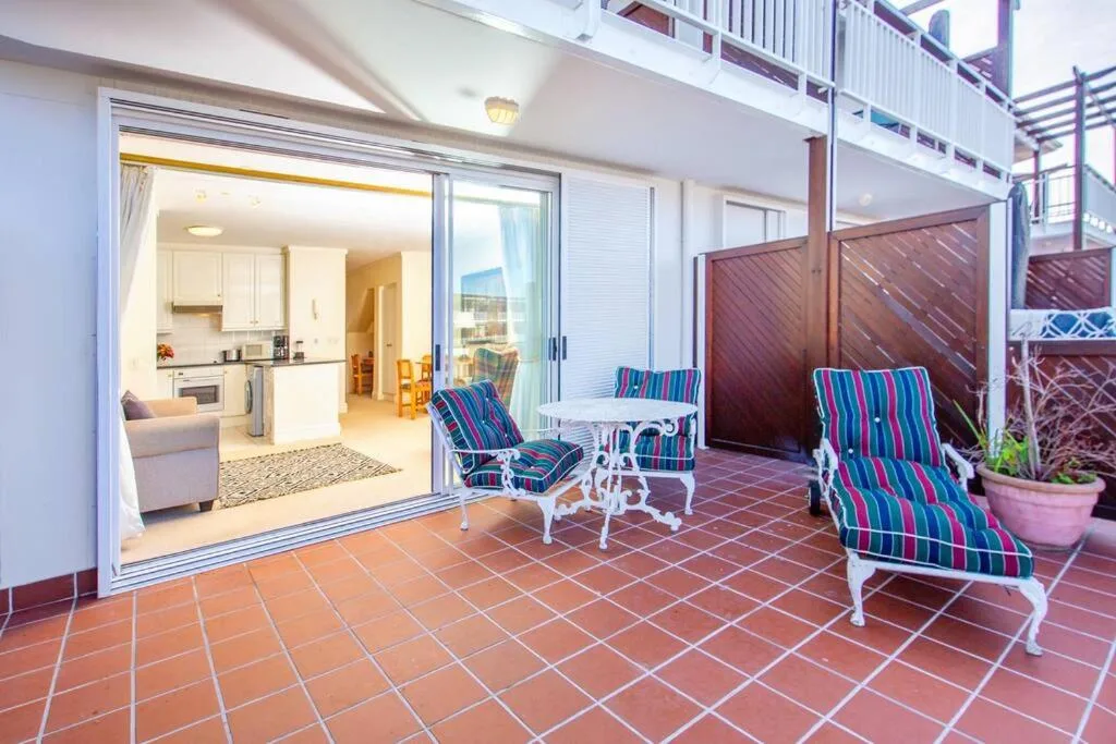 Spacious terracotta-tiled deck with striped loungers and mountain views