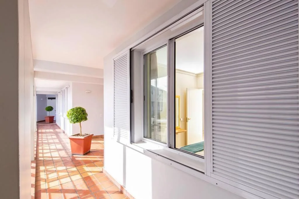 Modern hallway with terracotta tiles, potted plants, and sliding glass doors