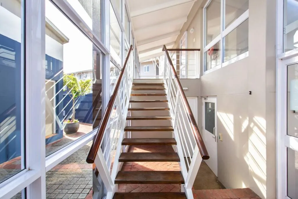 Bright staircase with wooden steps and white railings leading upward