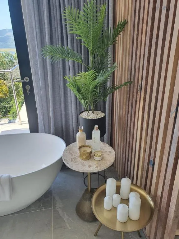 Modern bathroom with freestanding tub, potted palm plant, and decorative candles