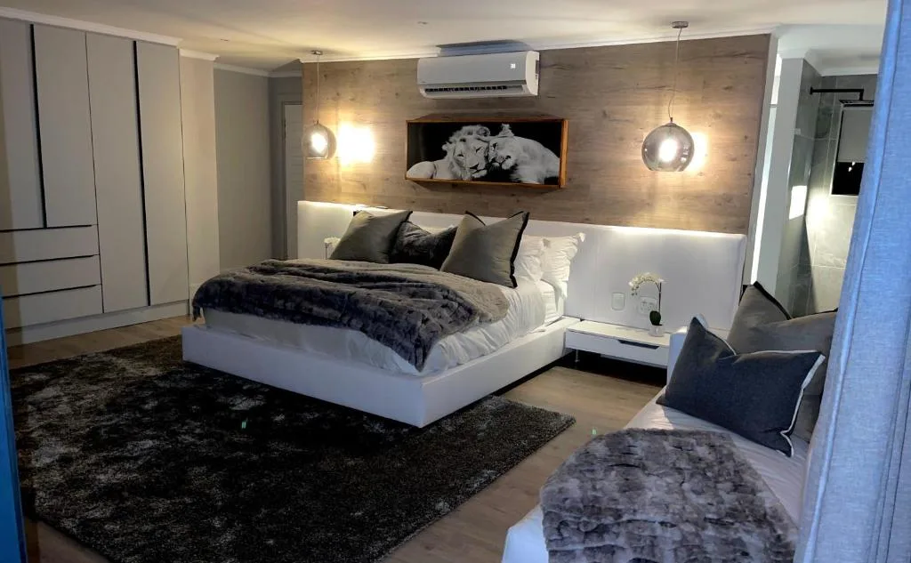 Modern bedroom with white platform bed, dark accent wall, pendant lighting, and wildlife artwork