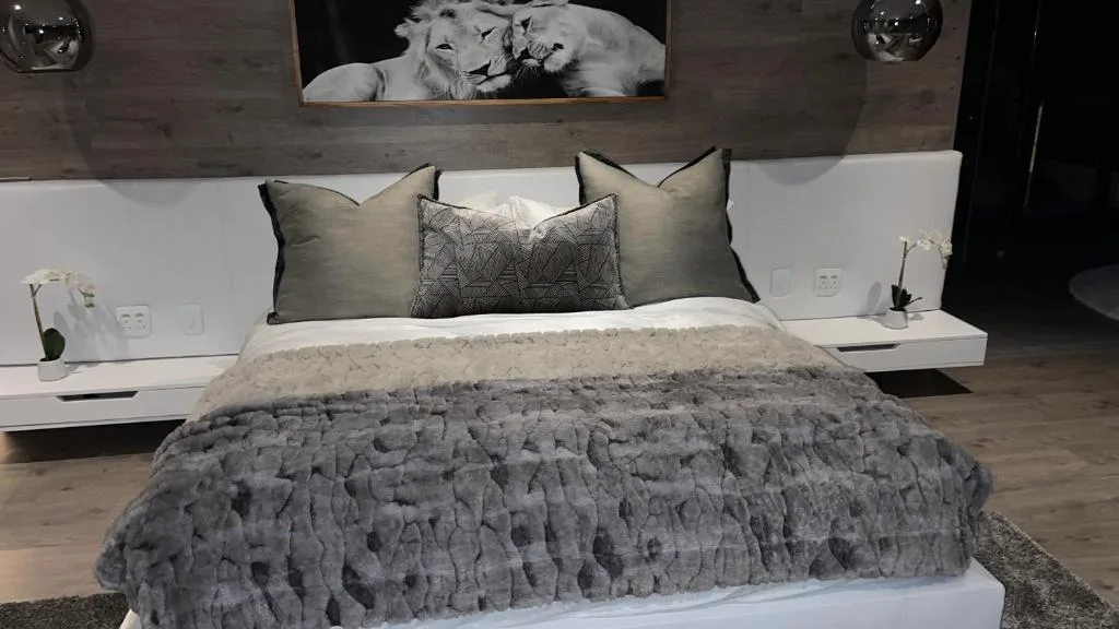 Modern bedroom with textured gray bedding, decorative pillows, and artwork above headboard