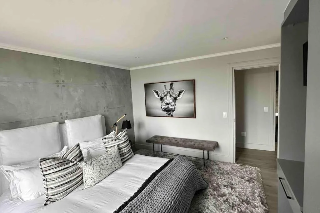 Modern bedroom with gray upholstered bed, striped pillows, and giraffe artwork