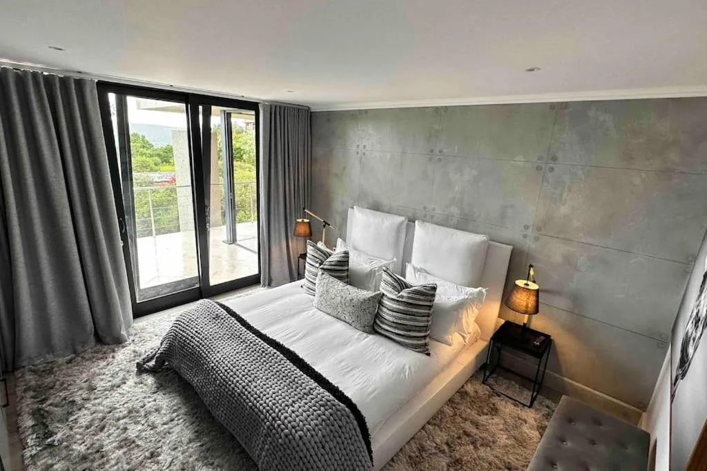 Modern bedroom with king bed, gray upholstered headboard, deck access doors