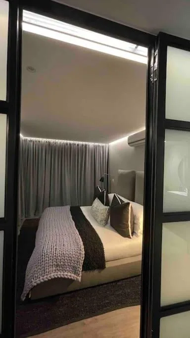 Modern bedroom with queen bed, grey curtains, ambient ceiling lighting