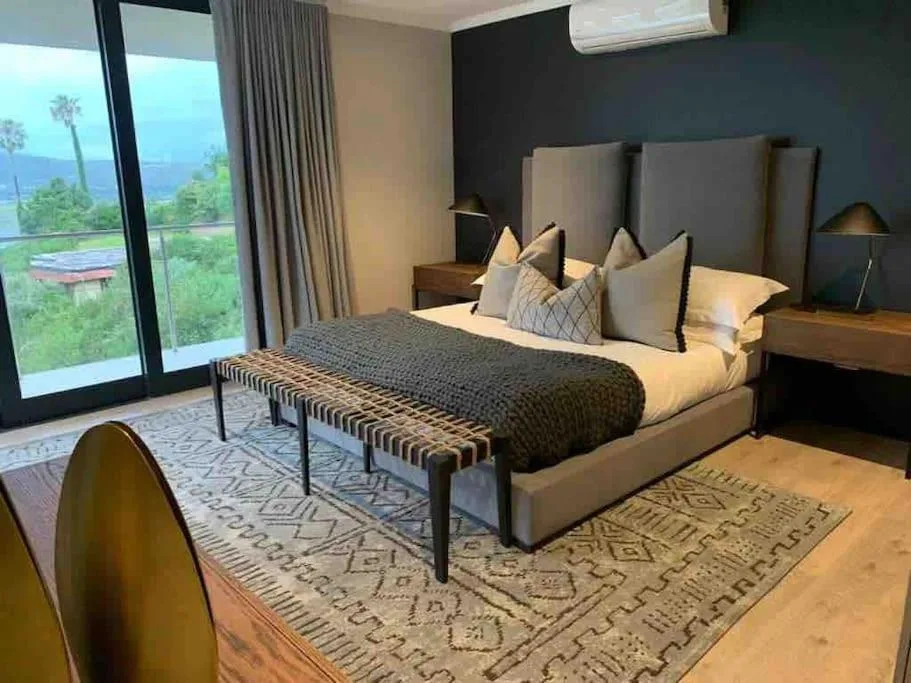 Modern bedroom with ocean view through large sliding doors and contemporary furnishings