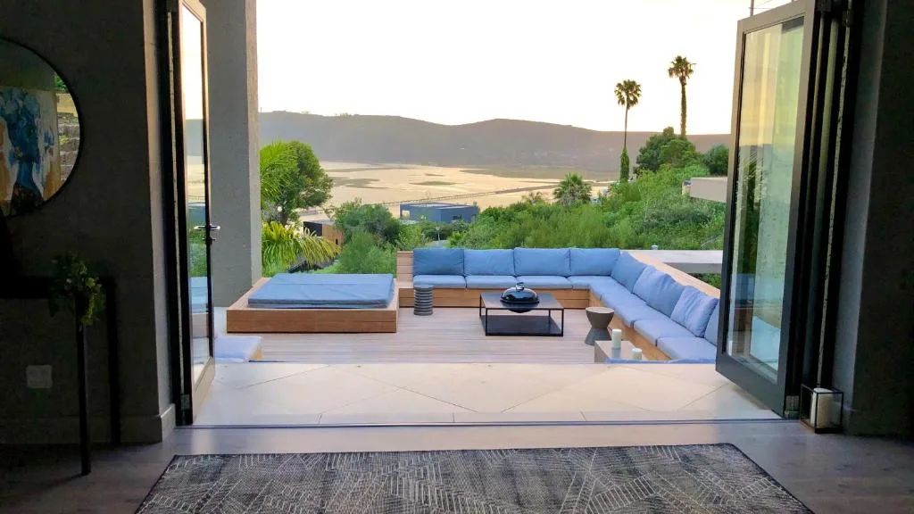 Modern wooden deck with blue cushioned seating and lagoon views at sunset