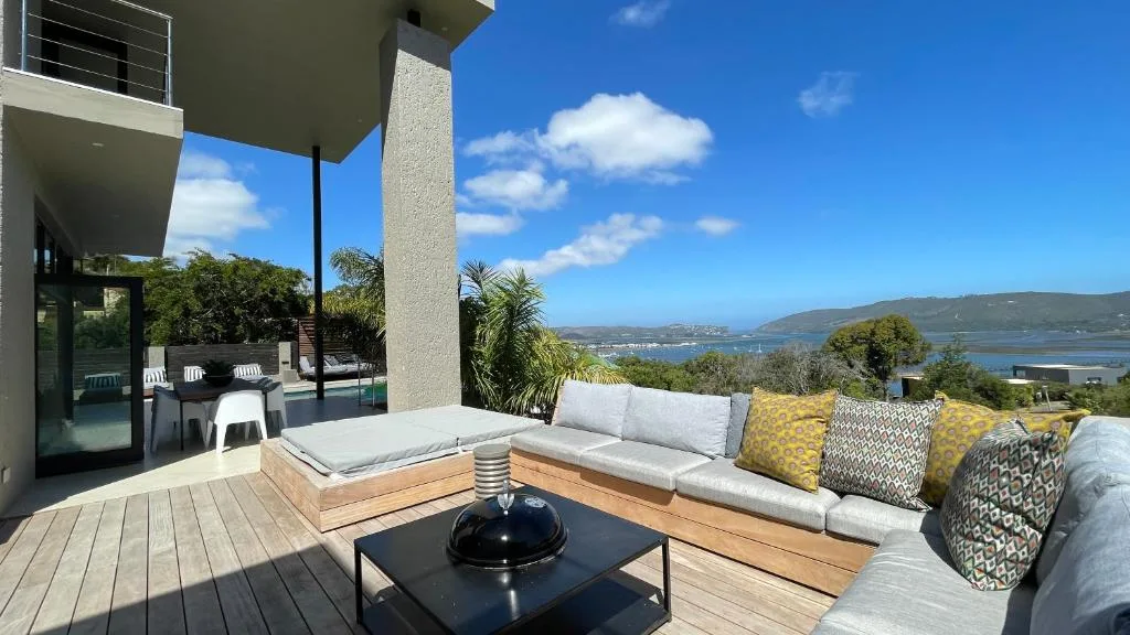 Wooden deck with built-in seating, cushions, and lagoon views beyond