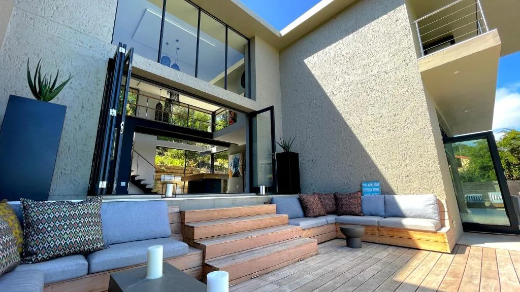 Modern outdoor patio with blue seating, wooden steps, and mountain views