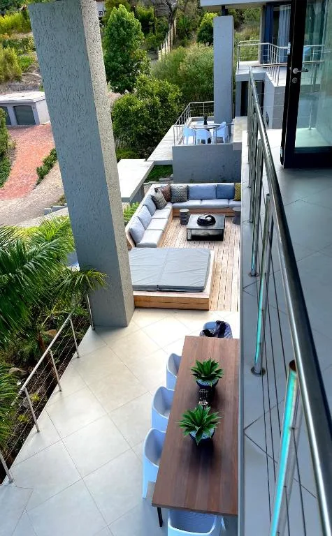 Modern outdoor deck with seating area, dining table, and landscaped garden views