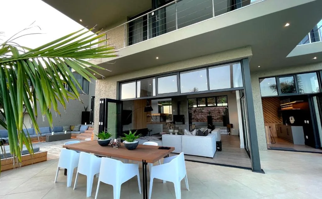 Modern outdoor patio with dining table, lounge seating, and tropical plants