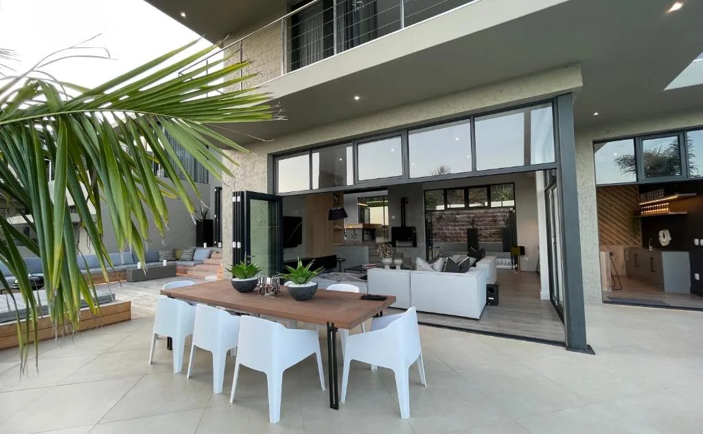 Modern outdoor patio with dining table, lounge area, and large glass doors