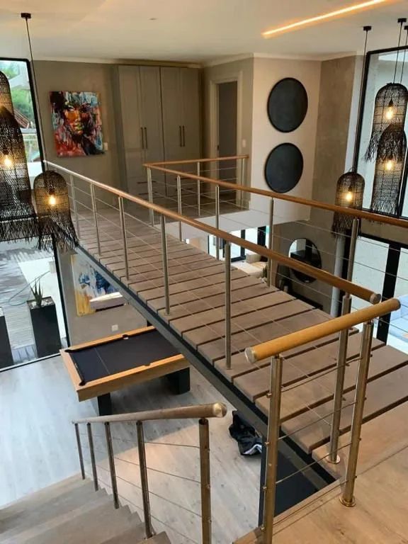 Modern interior staircase with wooden handrail and metal railings, pendant lighting