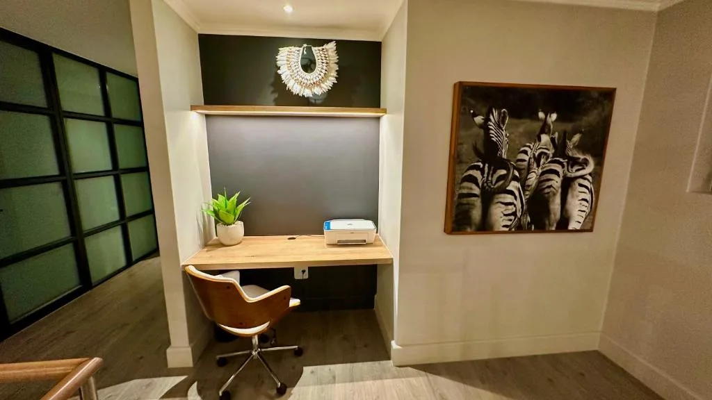 Modern home office nook with wooden desk, leather chair, and decorative wall art