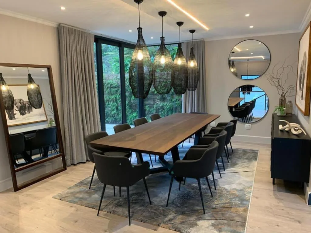Modern dining room with wooden table, black chairs, and pendant lights