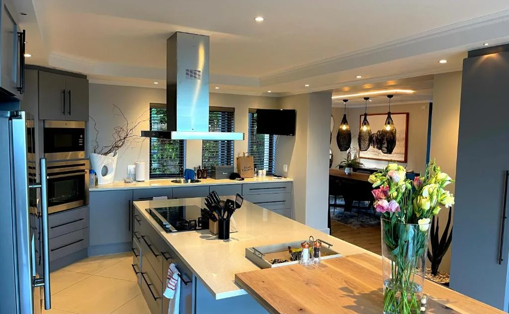 Modern kitchen with island bench, gray cabinetry, stainless steel appliances, and pendant lighting
