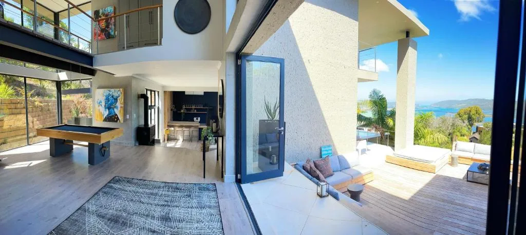 Open-plan lounge with pool table and ocean views through glass doors