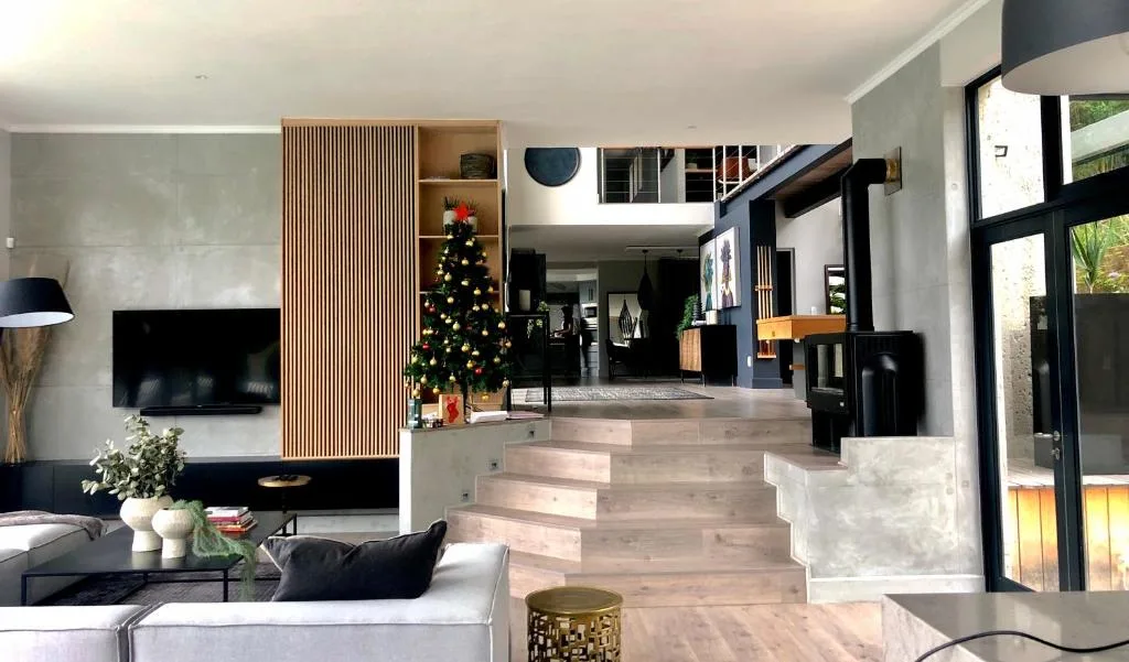 Modern open-plan lounge with TV, sofa, and decorative Christmas tree