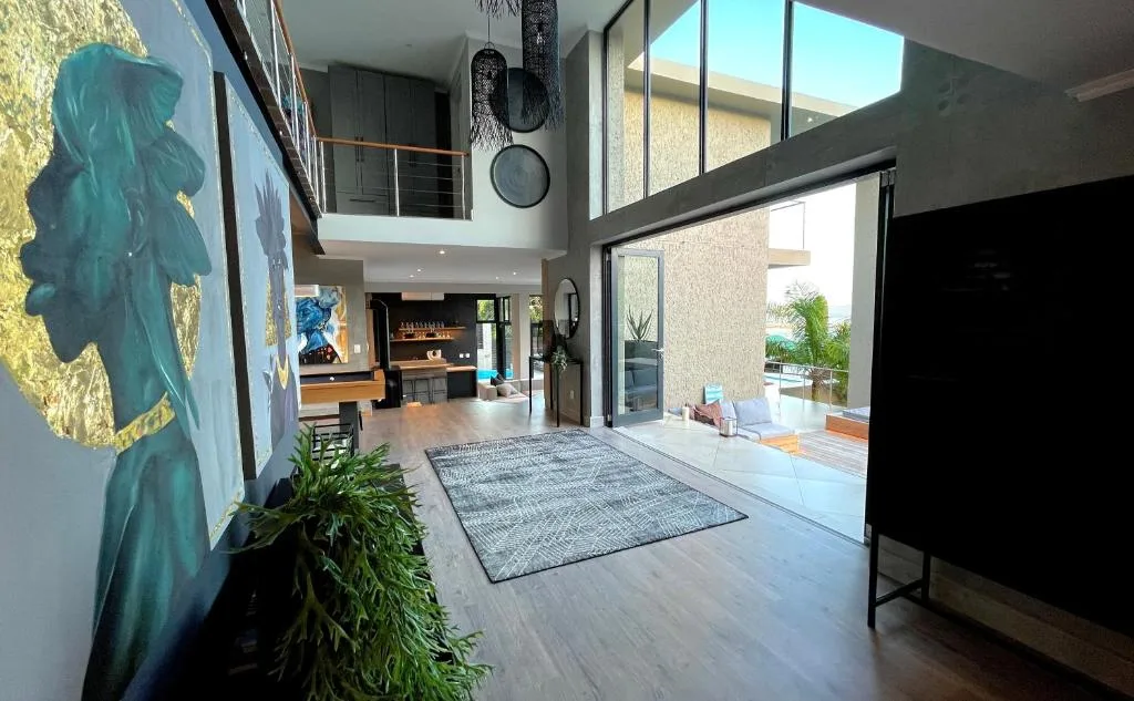 Modern open-plan lounge with high ceilings, artwork, and outdoor access