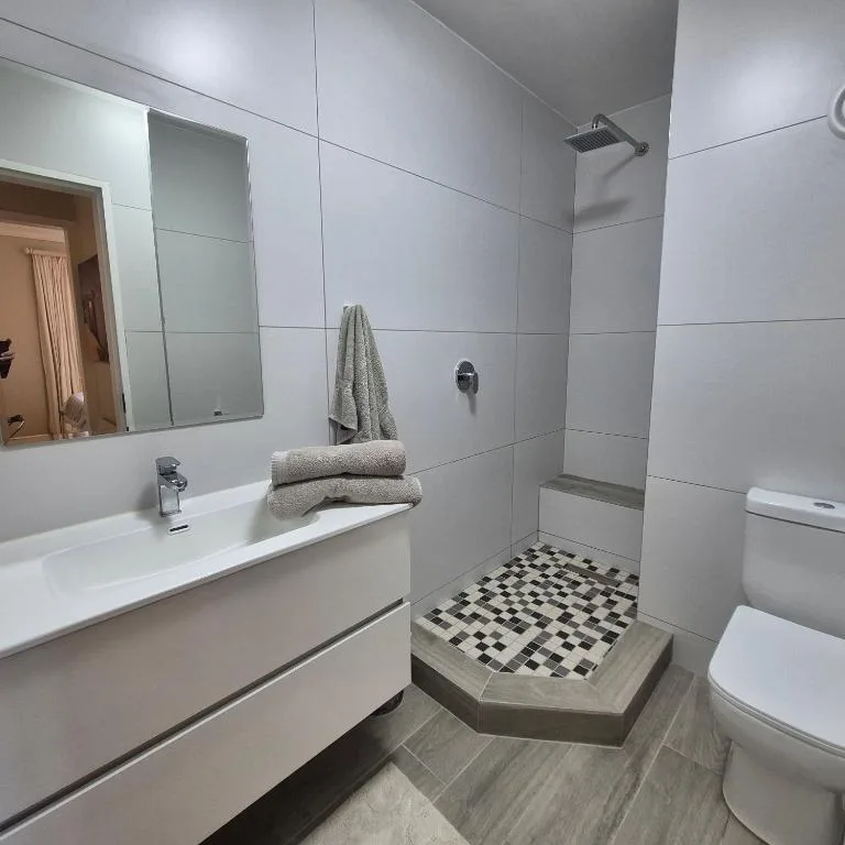 Modern bathroom with vanity, shower enclosure, and monochrome tiled floor
