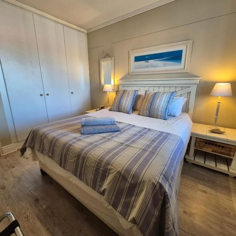 Bright bedroom with striped bedding, white wardrobe, and coastal decor
