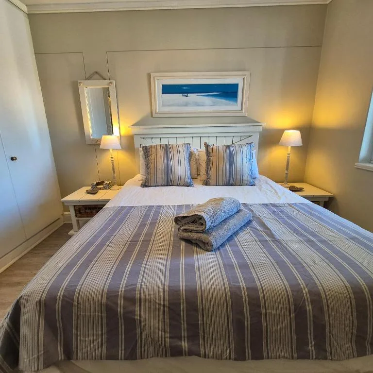Comfortable double bed with striped bedding and coastal-themed pillows in bright bedroom
