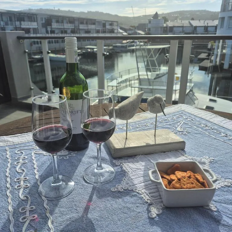 Waterfront deck with wine glasses, bottle, and snacks overlooking lagoon