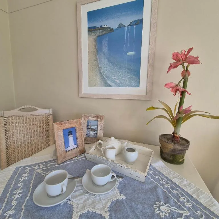 Tea service setup with cups, teapot, framed coastal artwork and fresh flowers