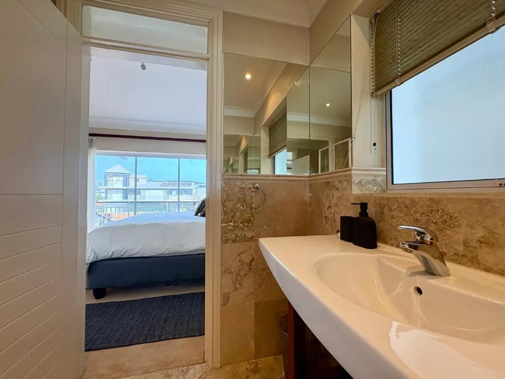 Modern bathroom with vanity sink, marble accents, and ocean view through glass doors