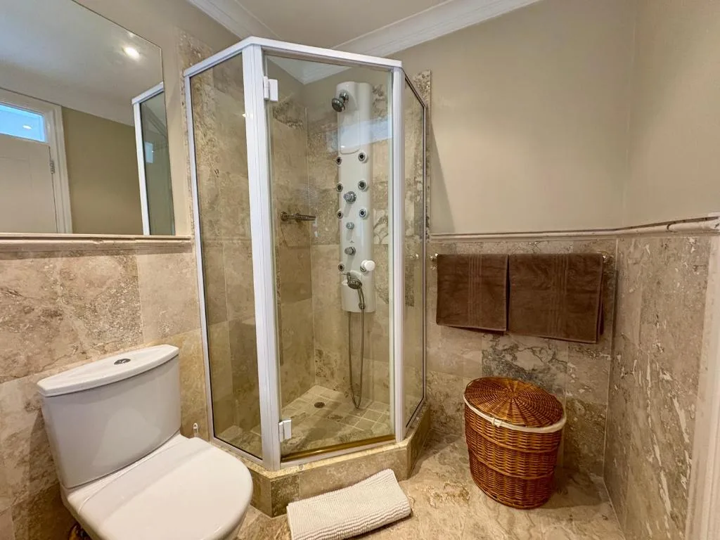 Spacious bathroom with corner shower enclosure and white toilet