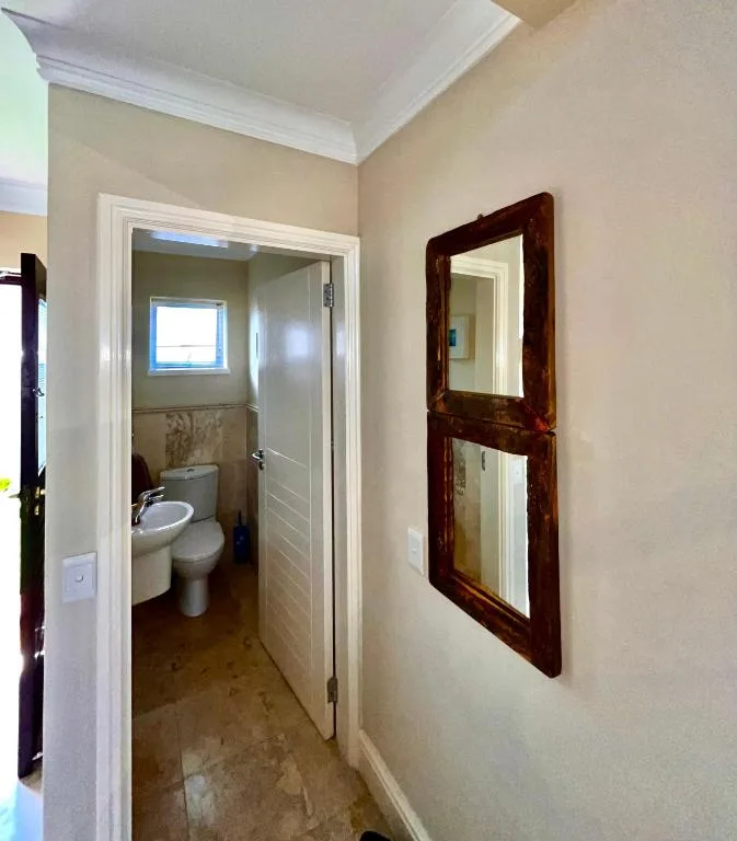 Bathroom entrance with toilet, sink, and small window visible inside