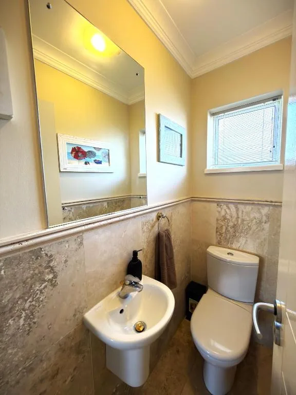 Bathroom with sink, toilet, large mirror, and sunny yellow walls