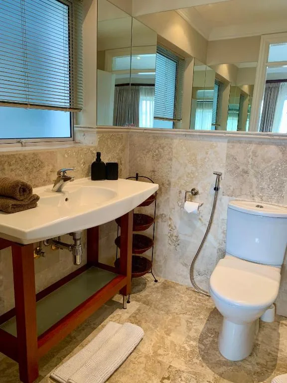 Bathroom with dual vanity sink, mirror, and toilet in cottage